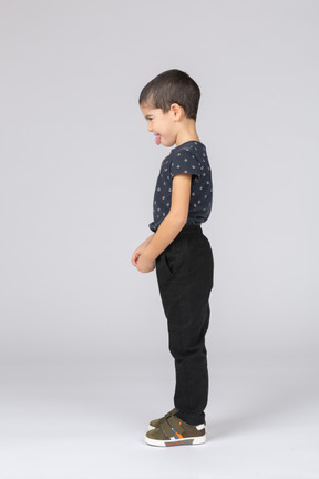 Vista lateral de um menino fofo em roupas casuais fazendo caretas