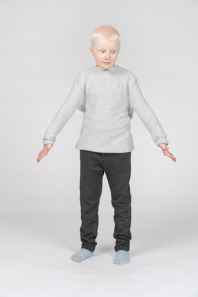 Little boy standing with spread arms and looking aside
