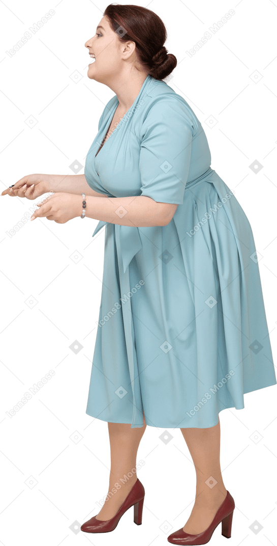 一个快乐的女人在蓝色连衣裙摆姿势的侧视图