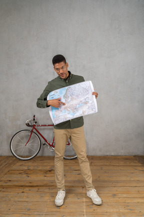 Front view of a man holding and pointing at a map