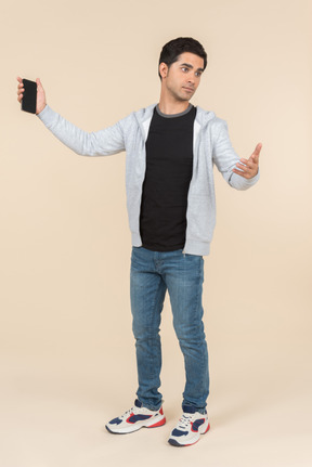 Giovane uomo caucasico che punta a smartphone che sta tenendo