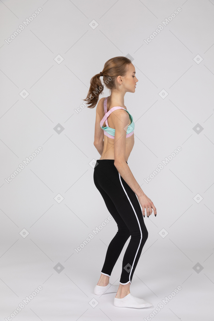 Three-quarter back view of a teen girl in sportswear tilting shoulders
