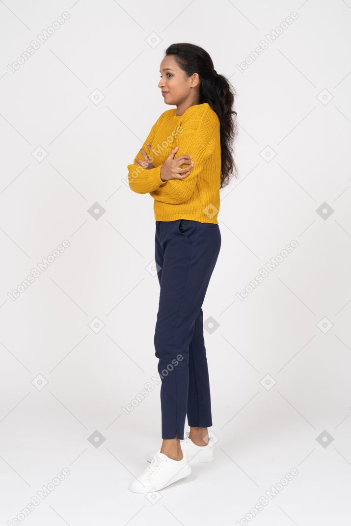 Vista laterale di una ragazza in abiti casual in posa con le braccia incrociate