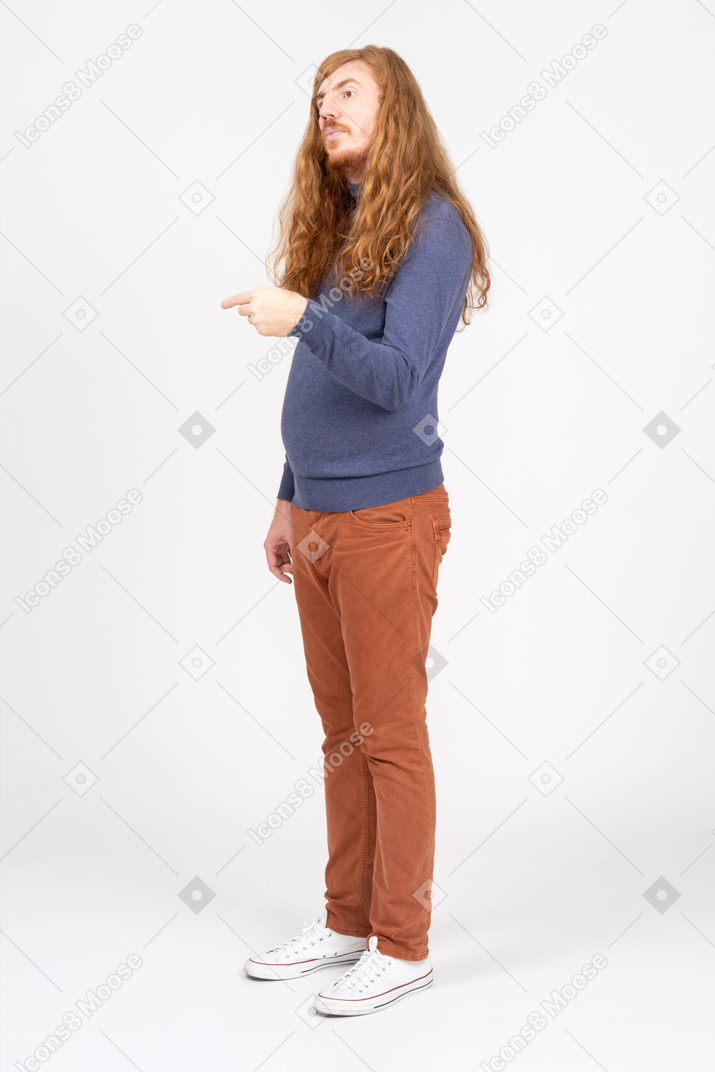 Vista lateral de un joven con ropa informal señalando con el dedo