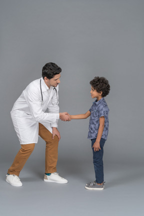 Pequeno paciente e médico apertando as mãos