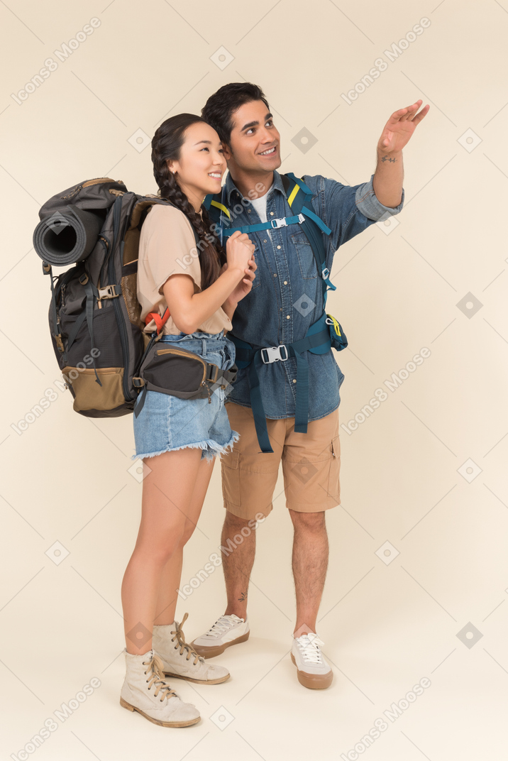 Young interracial couple of hikers looking at something up