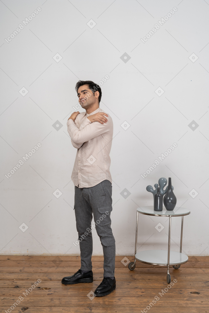Side view of a man in casual clothes hugging himself