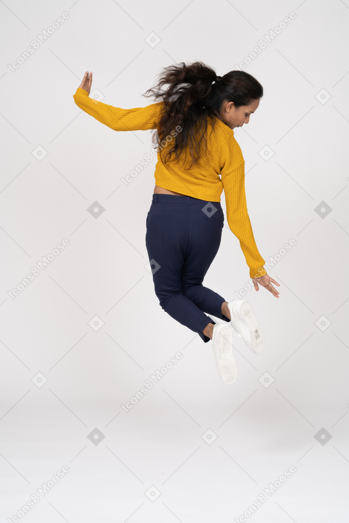 Vue arrière d'une fille en vêtements décontractés sautant et essayant de toucher son pied