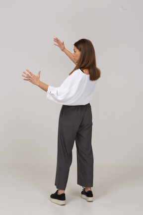 Vista posteriore di tre quarti di una giovane donna in abiti da ufficio che mostra una taglia di qualcosa