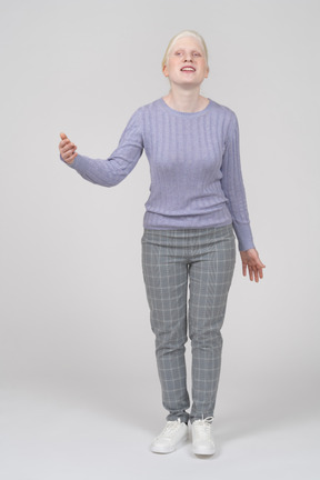 Front view of a young smiling woman standing and raising her hand