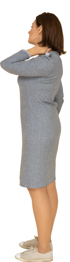 Vista laterale di una donna in abito grigio che soffre di dolore al collo