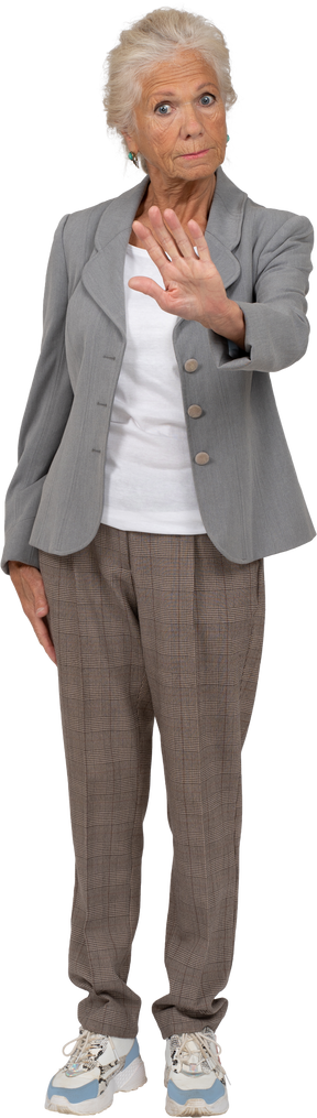 Vista frontal de una anciana en traje mostrando gesto de parada
