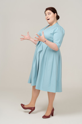 Mulher impressionada de vestido azul em pé de perfil