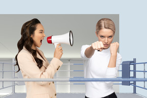 Woman shouting through megaphone at another woman in fighting stance