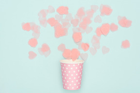 Confettis dispersés du gobelet en papier rose à pois