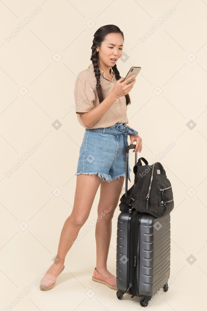 Annoyed female traveler using her smartphone