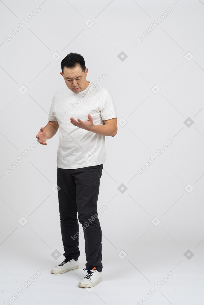 Front view of a confused man looking at hand