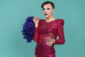 Portrait d'une drag queen tenant une perruque et une tasse en plastique