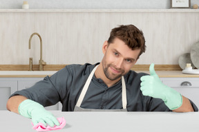 Hombre con guantes de goma limpiando la cocina