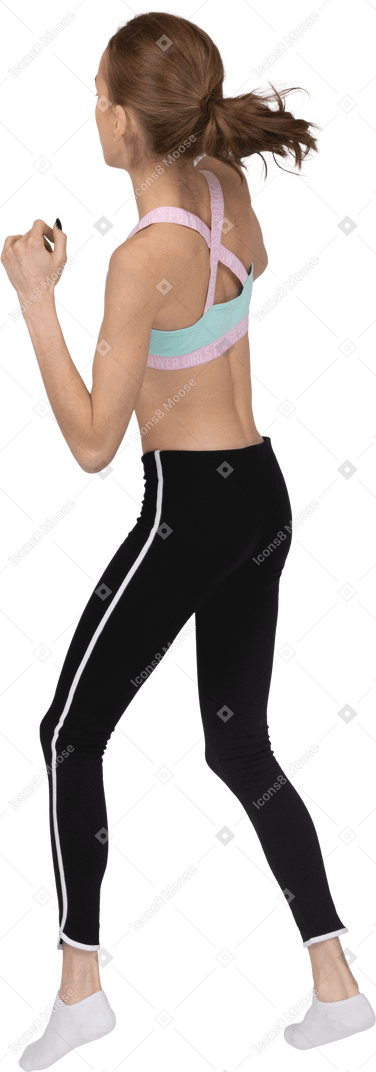 Vista posteriore di una ragazza adolescente in abiti sportivi che si fa avanti mentre stringe i pugni
