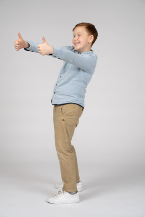 Vista lateral de um menino feliz, mostrando os polegares