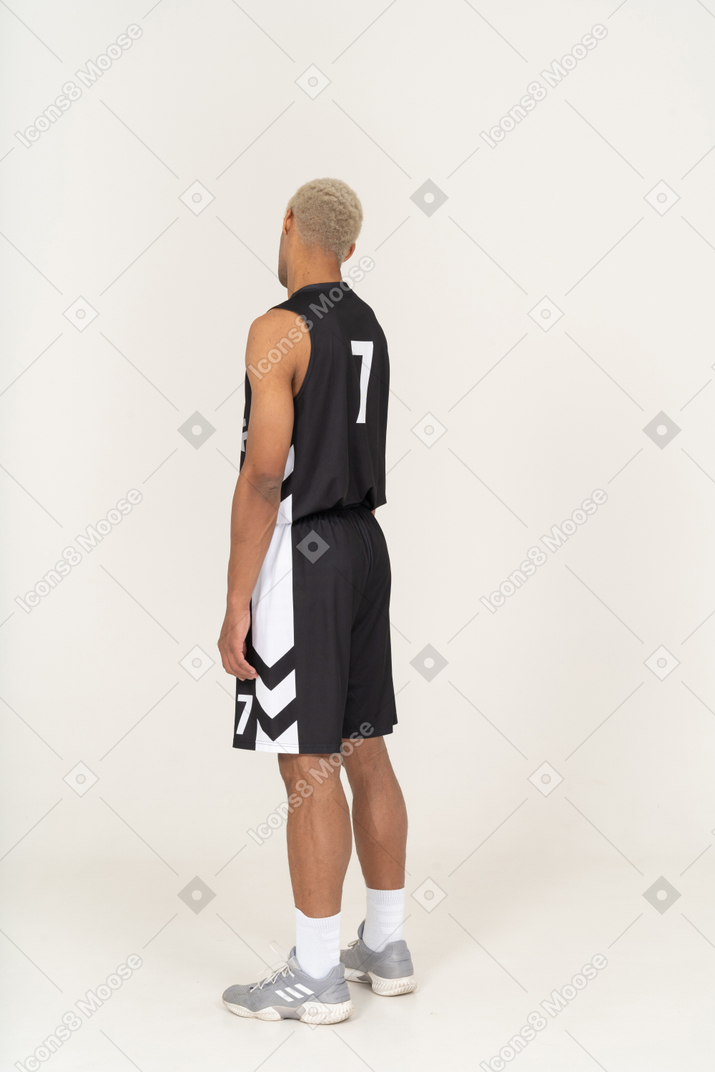 Vista posterior de tres cuartos de un joven jugador de baloncesto masculino cansado inclinando la cabeza