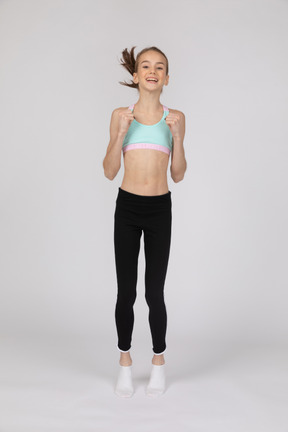 Una adolescente emocionada en ropa deportiva saltando