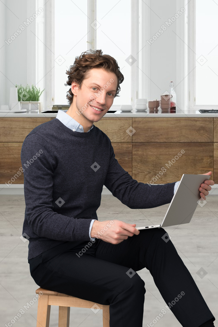 A man sitting on a stool using a laptop computer