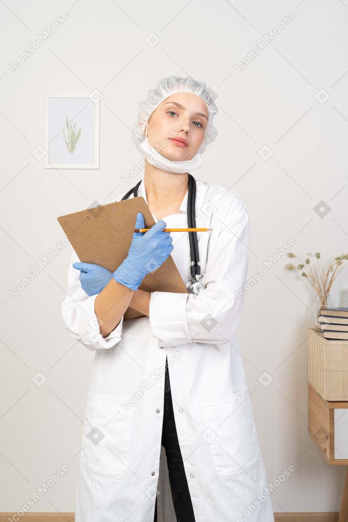 Vista frontal de una joven doctora sosteniendo un lápiz y una tableta