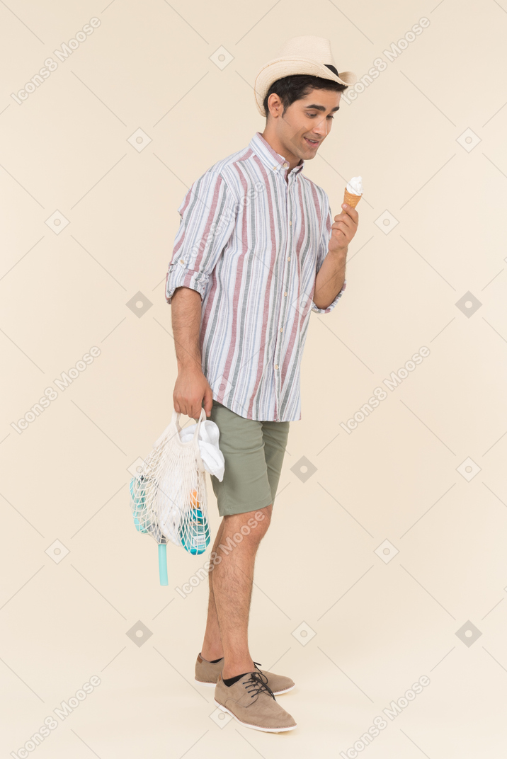 Young caucasian guy holding avoska and eating ice cream