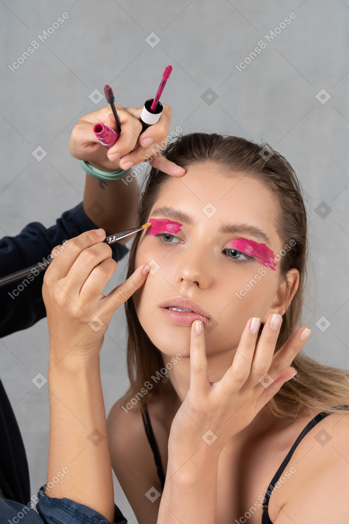 Close-up of a young woman having her make-up done