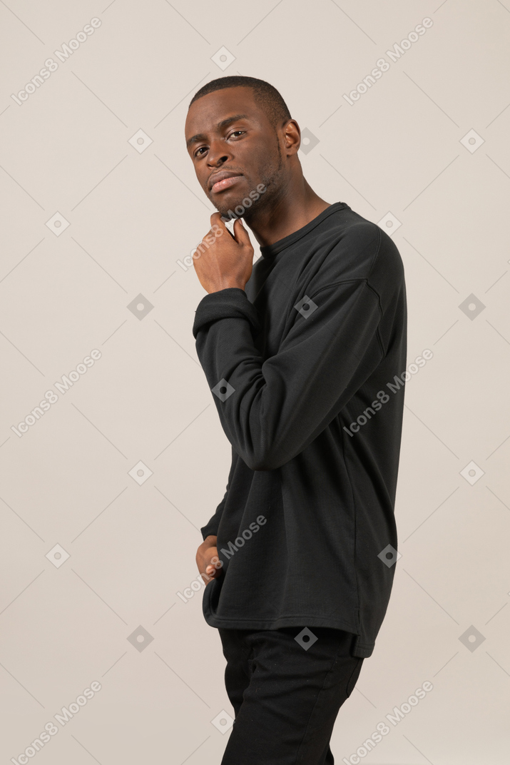 Young man touching chin and looking at camera