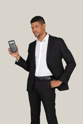 Young man in black suit pointing at calculator he's holding