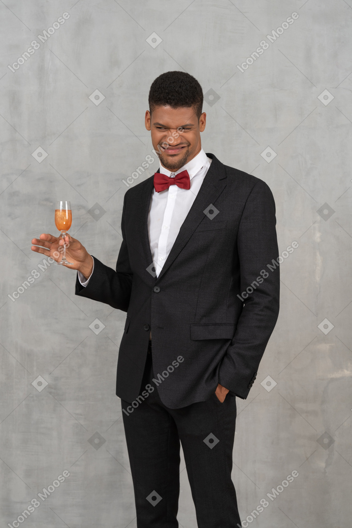 Man with a champagne glass in his hand scrunching up his face