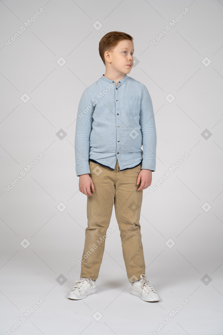 Vista frontal do menino em roupas casuais, olhando de lado