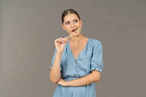 Vista frontal, de, un, mujer joven, en, vestido azul, cepillado, ella, dientes