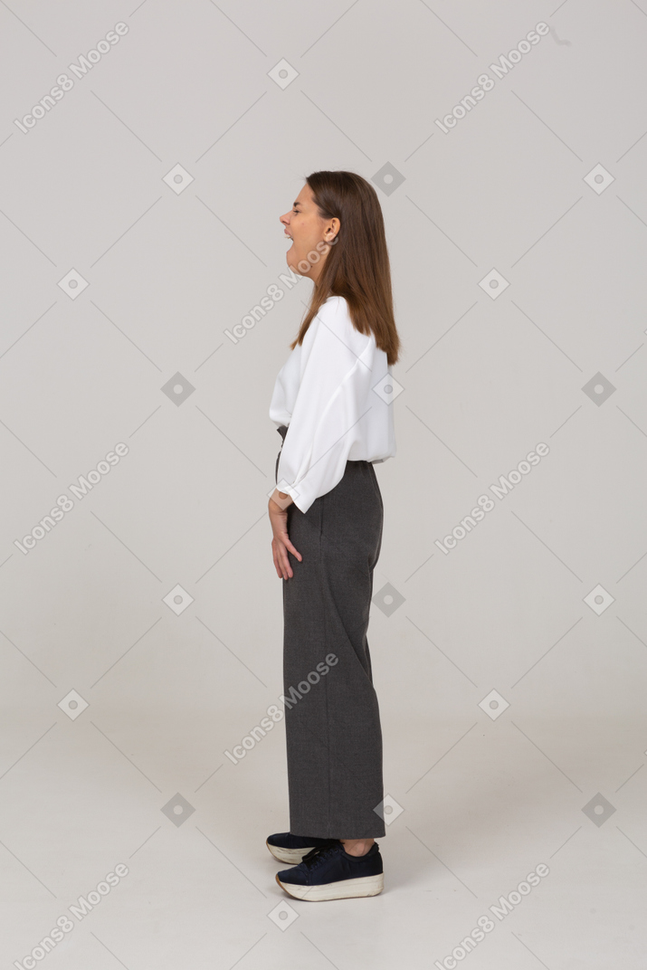 Vista lateral de uma jovem bocejando com roupas de escritório
