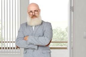 A bald man with a beard and glasses standing with his arms crossed