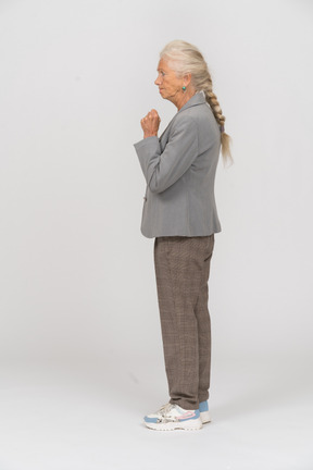 Vista lateral de uma senhora zangada com uma jaqueta cinza mostrando o punho