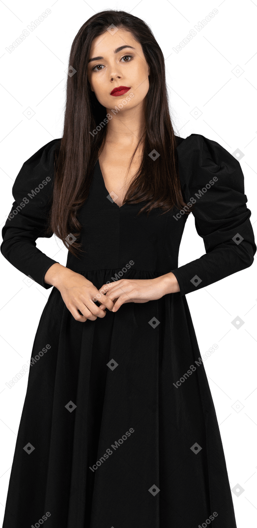 Vista frontale di una giovane donna in un abito nero in piedi ancora