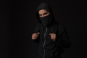 Hacker guy with covered face standing in the dark