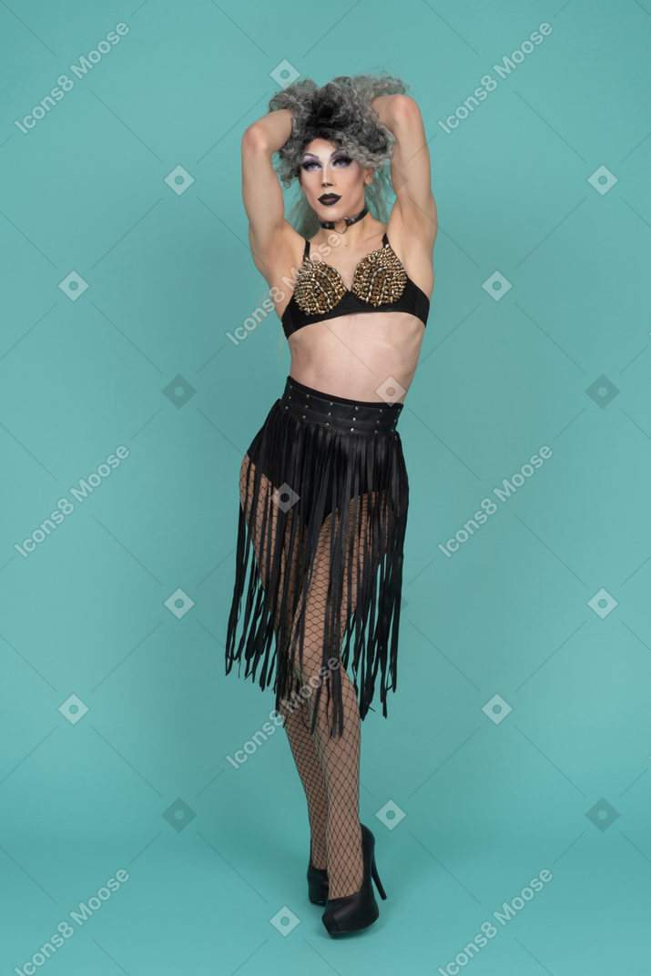 Front view of a drag queen in all black outfit pulling their hair up