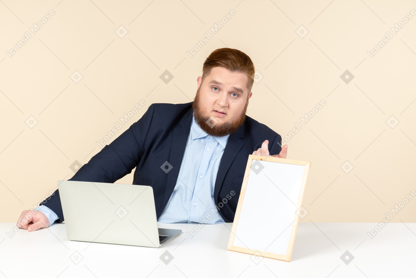 年轻的超重男子坐在桌前，拿着白色的相框