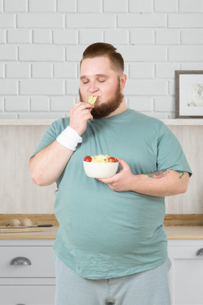 Man eating a salad in the kitchen