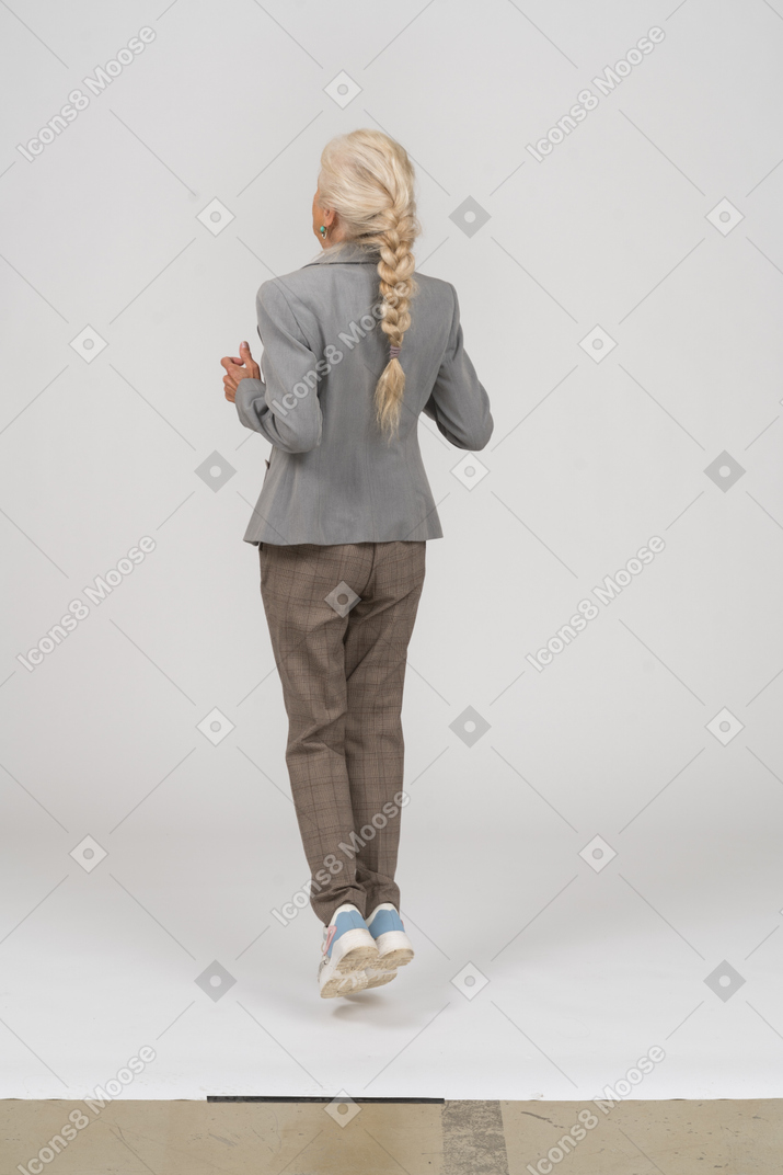 Back view of an old lady in suit jumping
