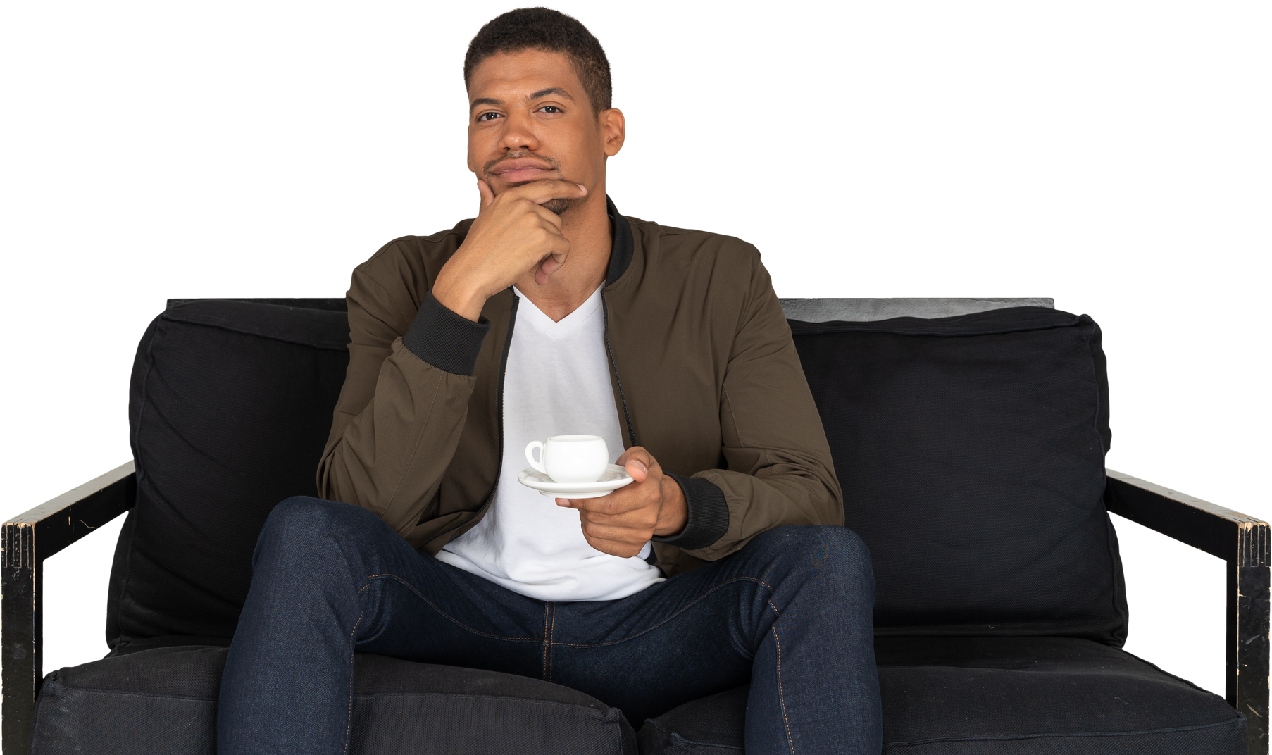 Front view of a young thoughtful man sitting on a sofa with a cup of coffee