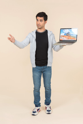 Young caucasian man presenting laptop