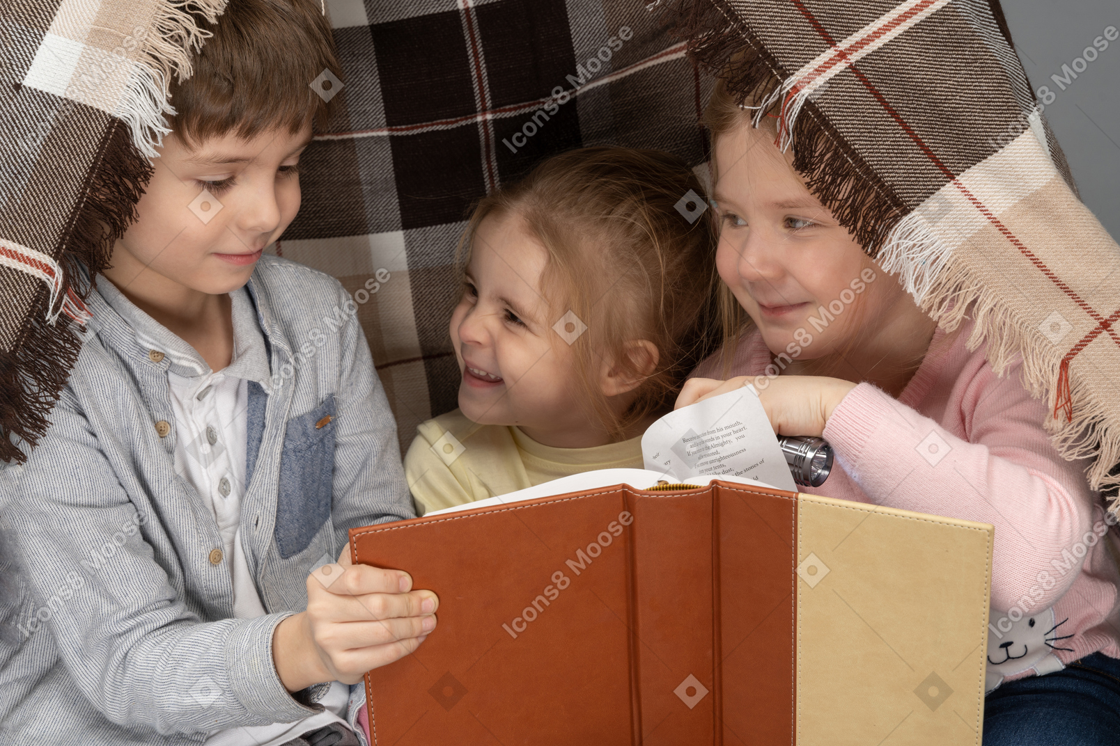 Children reading a book in a hut