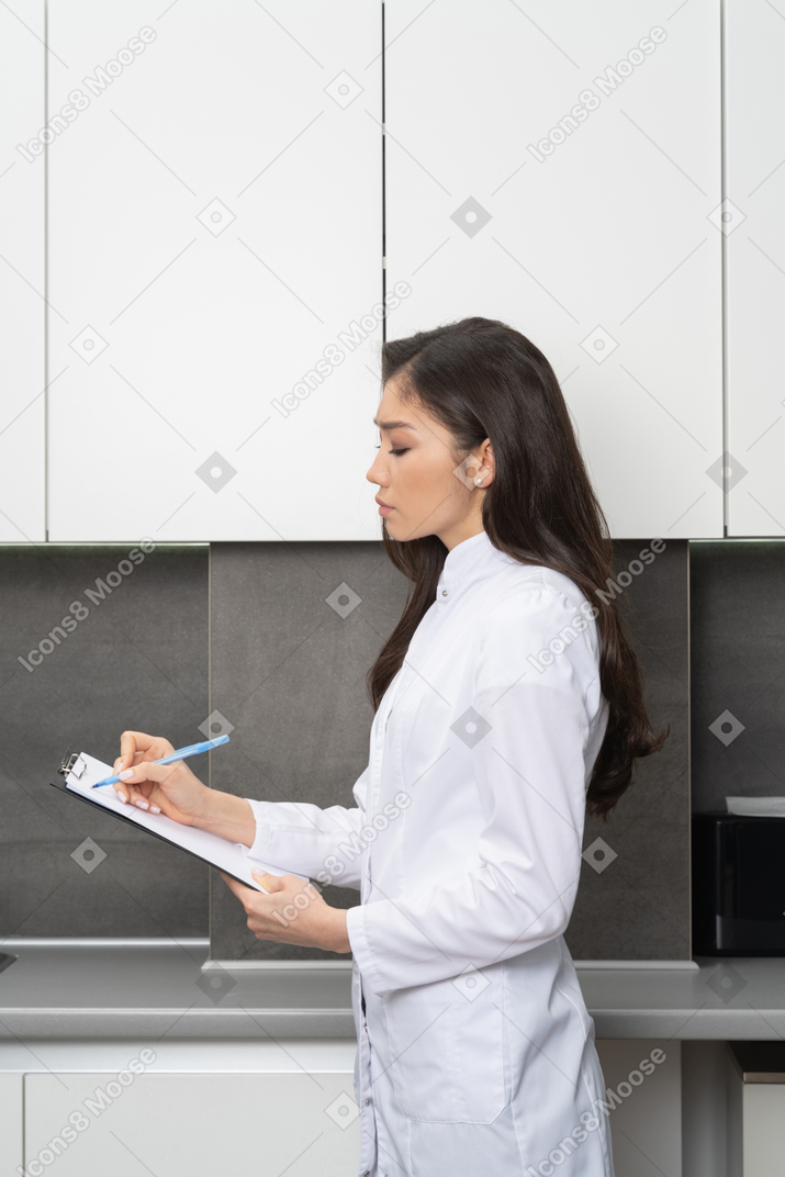 Side view of a female doctor taking notes in her tablet