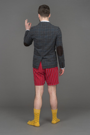 Nicht erkennbarer mann in roten shorts mit ok-zeichen